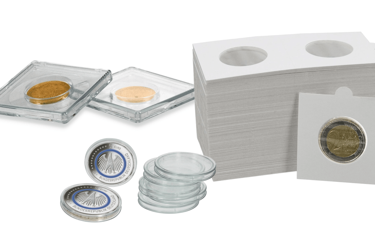 Clear acrylic coin holders, a stack of white card sleeves with circular cutouts, several clear round coin protectors, and a few sample coins inside holders.
