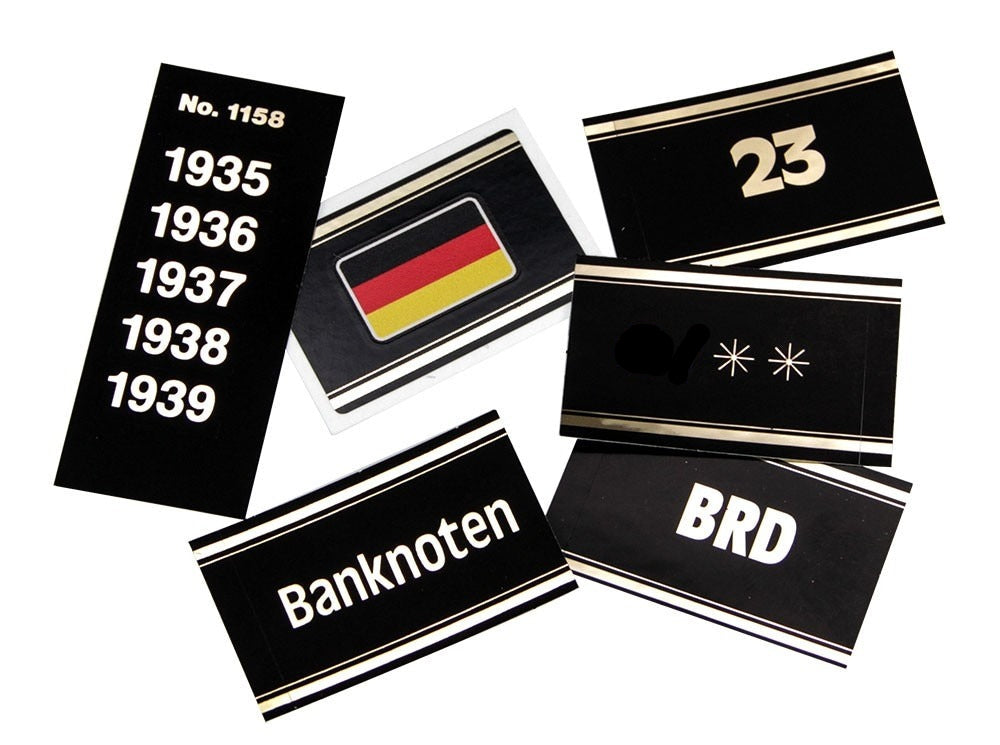 Collection of black and gold embossed labels with German text and symbols for album spine labeling/organizing on a white background