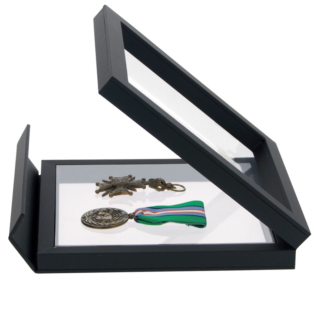 Open black square frame/shadowbox with transparent window made of film that will be molded to military medals once closed on a white background
