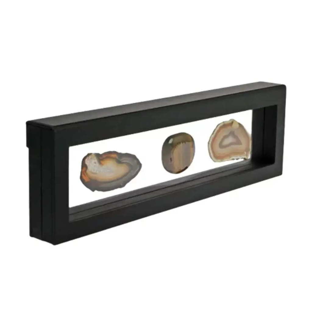 Black rectangular frame/shadowbox with transparent window made of film that is molded to a collection of agate slices on a white background