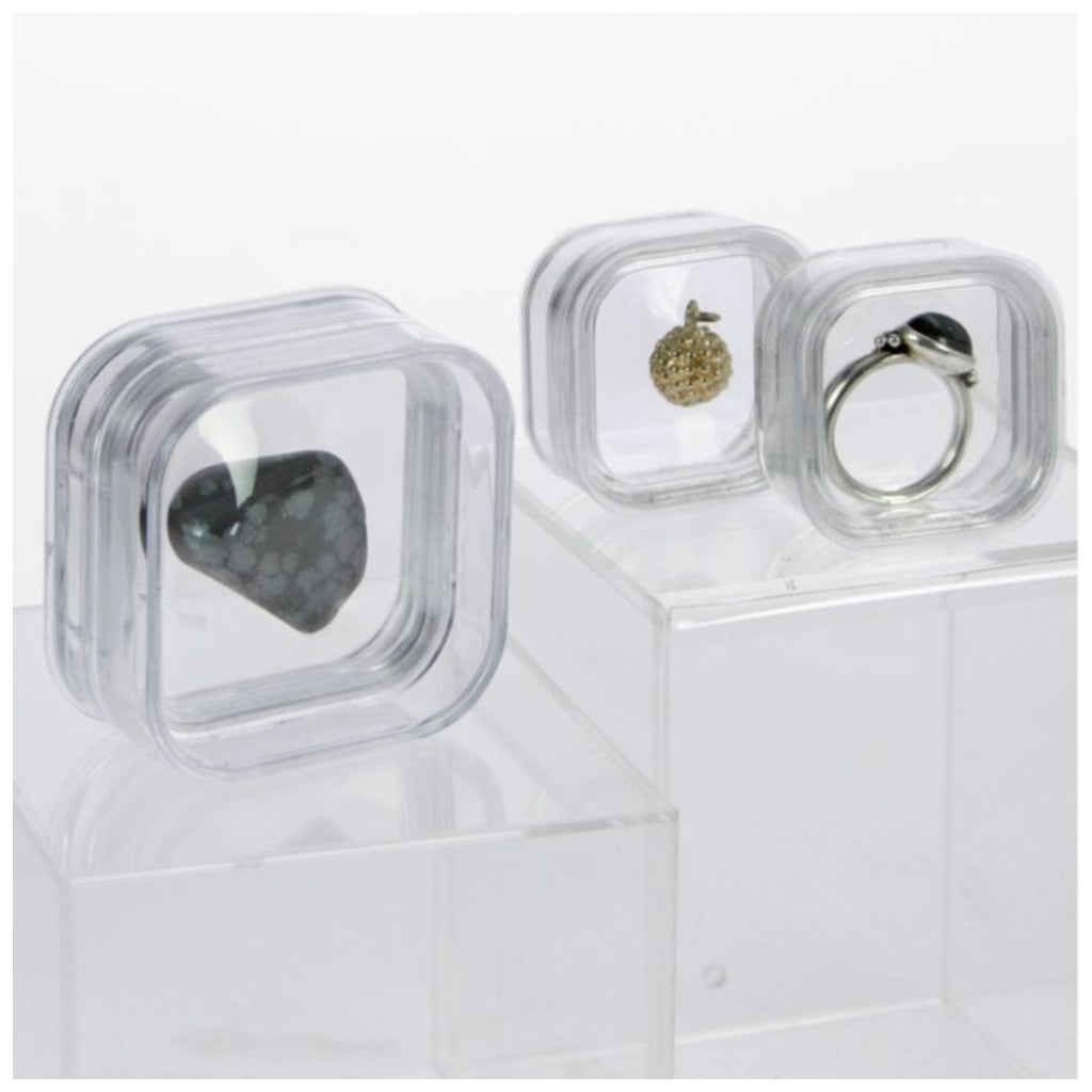 3 clear containers with internal flexible film molded to a stone, a pendant and a ring on a white background