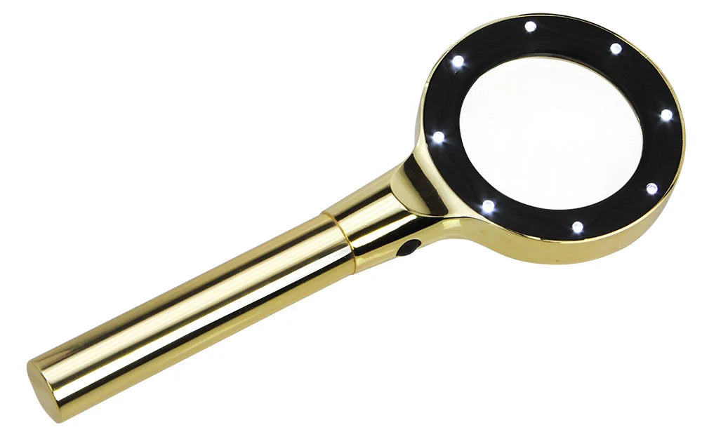 Handheld shiny gold magnifying glass with LED lights inside a black rim and a gold handle with black on/off button on a white background