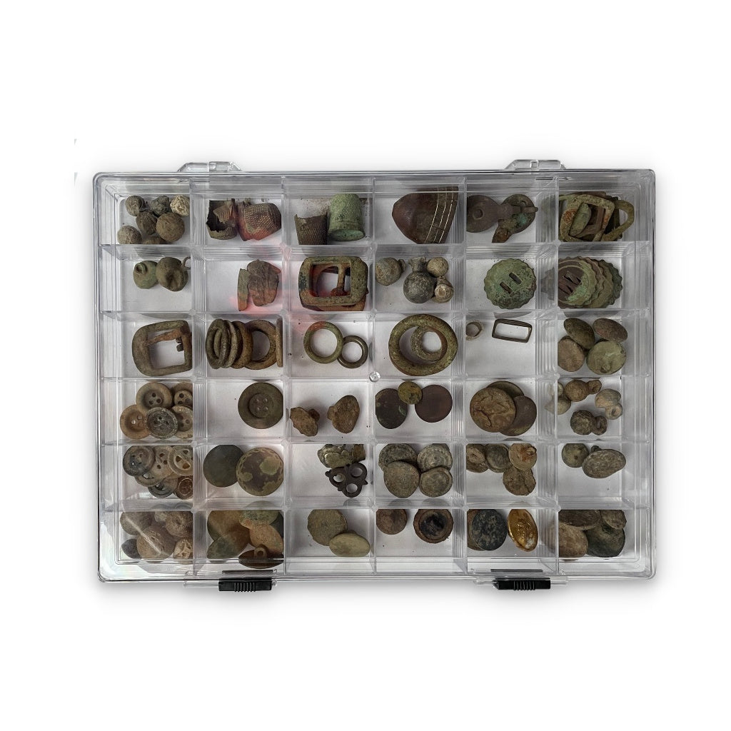 Collection of ancient coins and artifacts in a clear acrylic box with 36 compartments on a white background