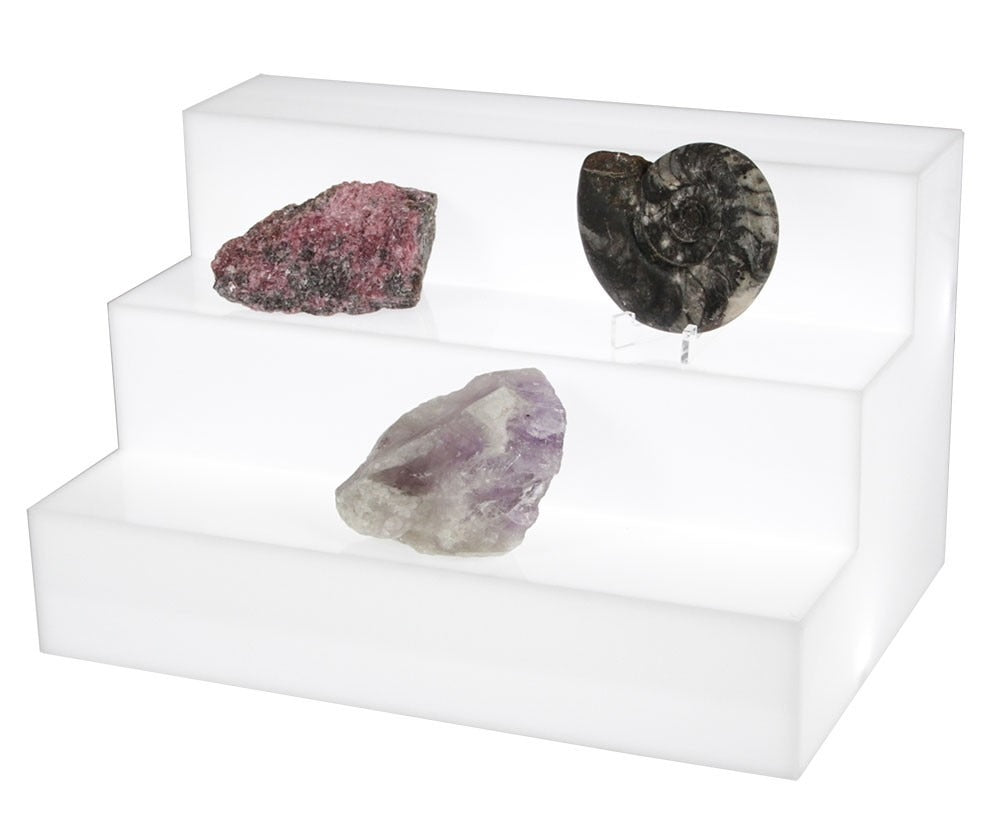 Three different rocks displayed on the illuminated tiered display steps from SAFE on a white background