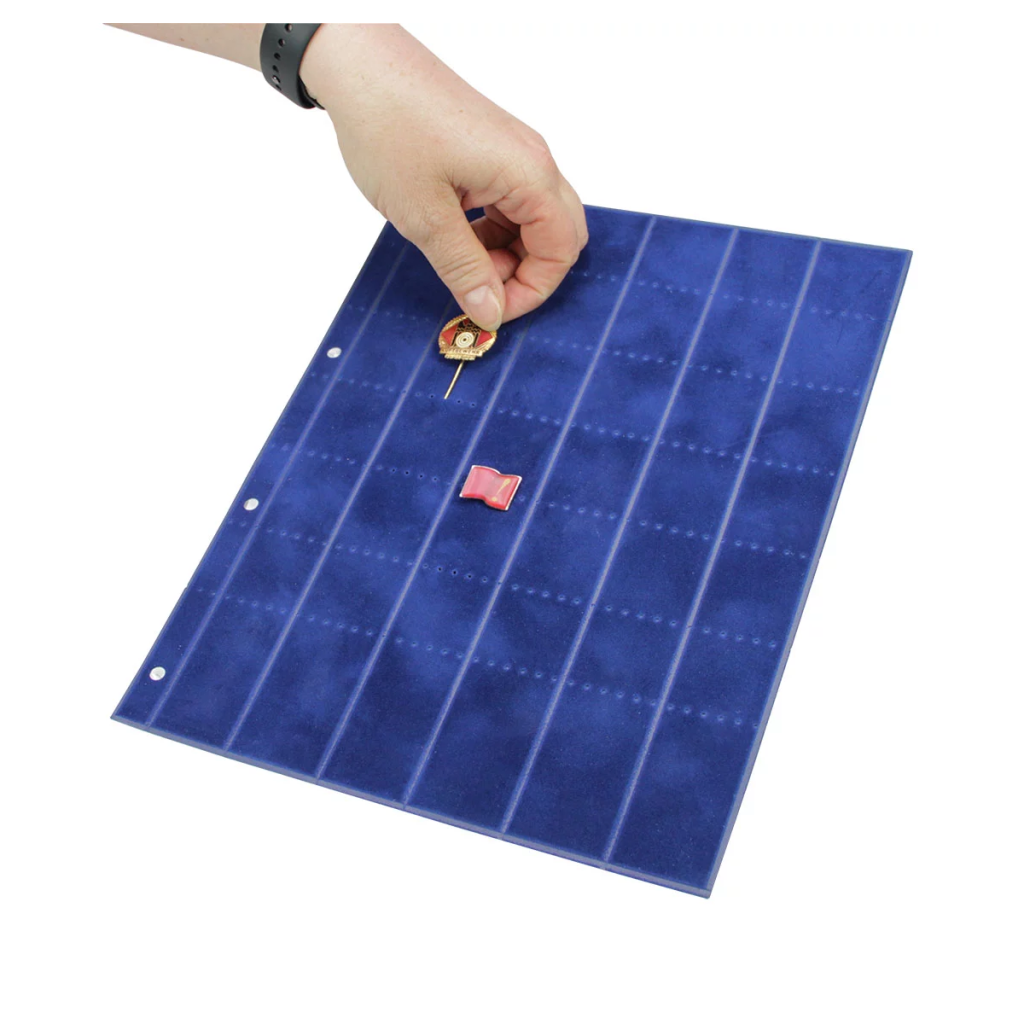 Hand placing a small lapel pin on a blue velvet pin page with grid markings on a white background