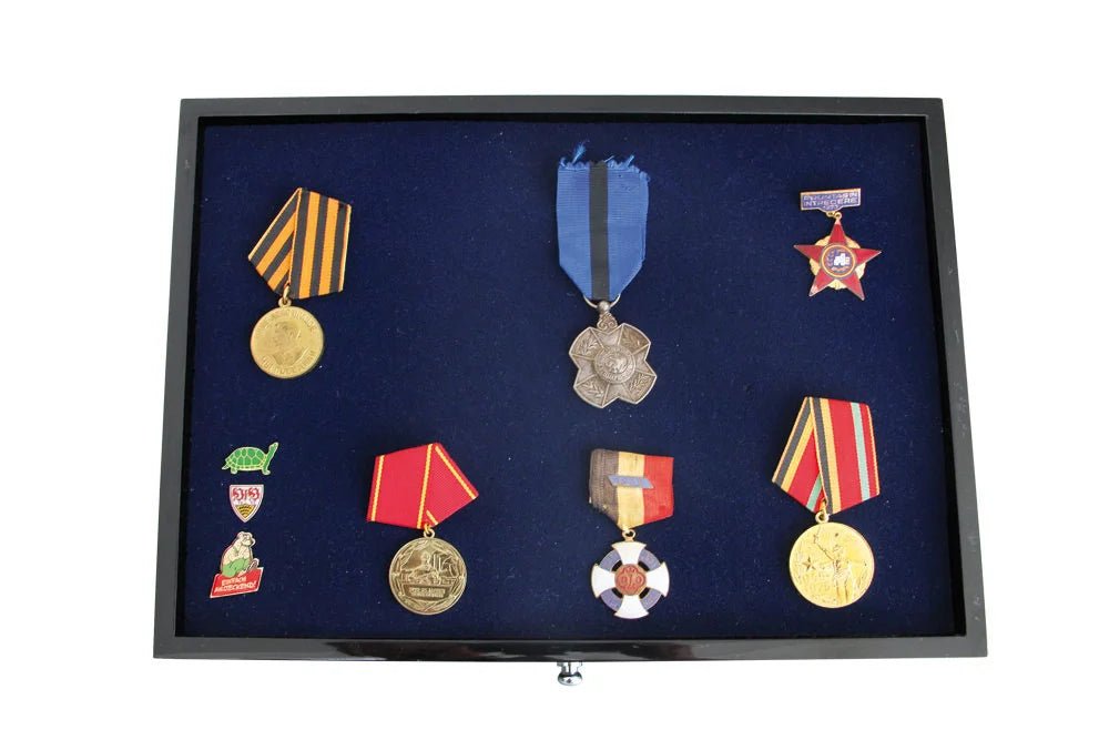 Black collection drawer with blue interior tray displaying a collection of military medals and pins on a white background