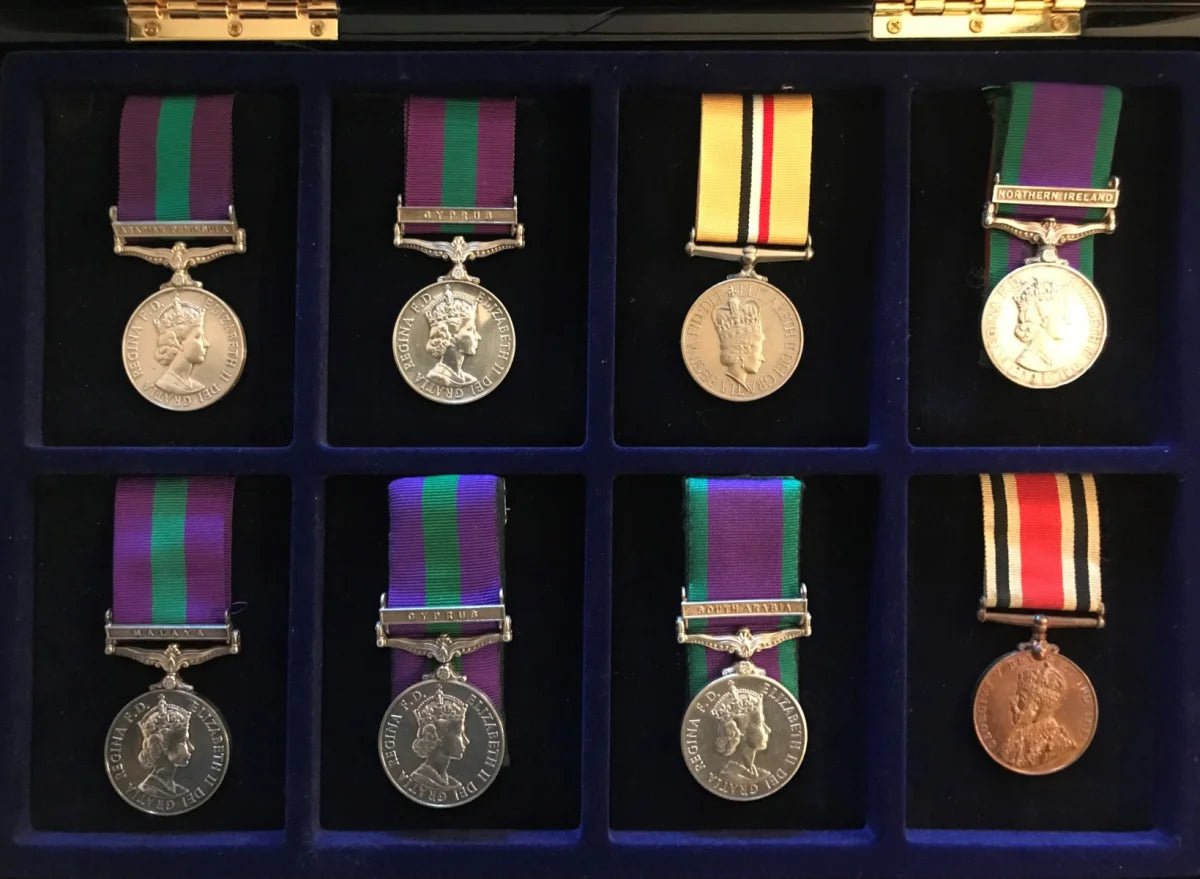 Set of military medals with ribbons in a display case on blue velvet removable pillows.