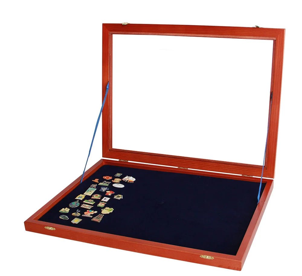 Wooden display case with an open glass lid displaying various collectible pins on a blue velvet insert on a white background.
