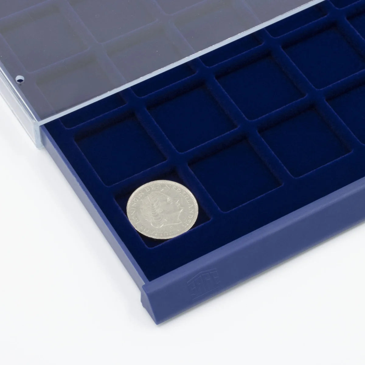 Detail shot of open acrylic stackable drawer unit with a blue velvet tray and square compartments for coins on a white background