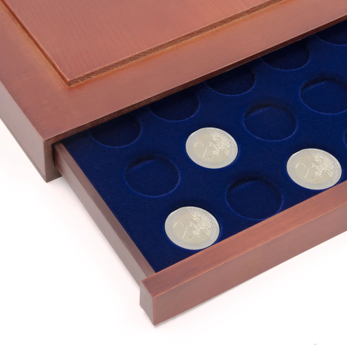 Detail shot of open wooden stackable drawer unit with a blue velvet tray with circular compartments holding coins on a white background