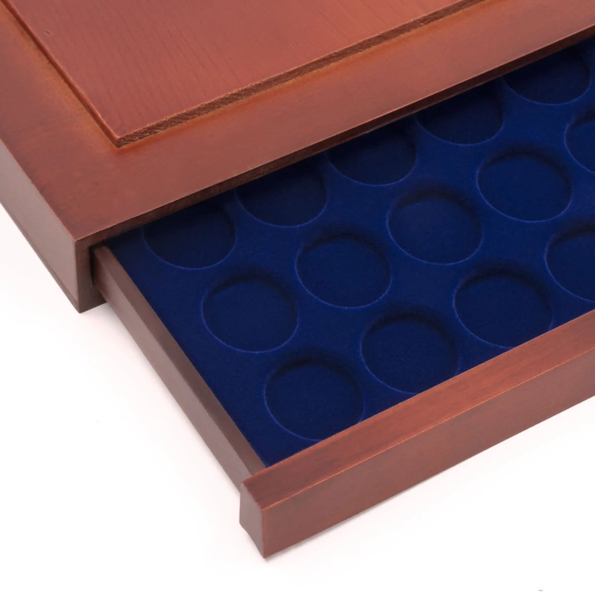 Detail shot of open wooden stackable drawer unit with a blue velvet tray with circular compartments for coins on a white background