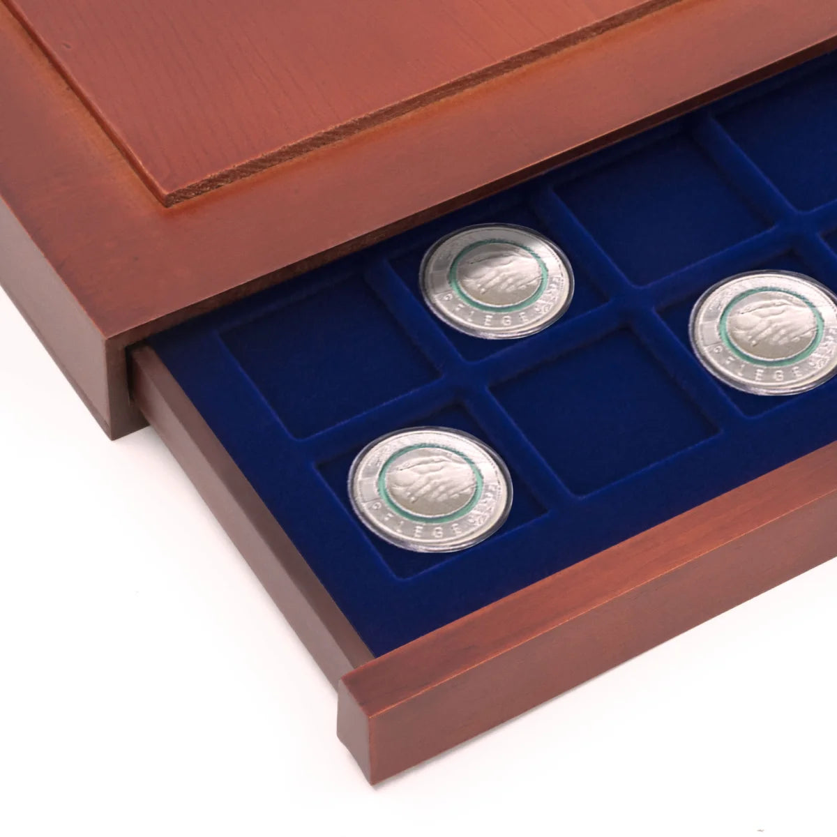 Detail shot of open wooden stackable drawer unit with a blue velvet tray with square compartments holding coins on a white background