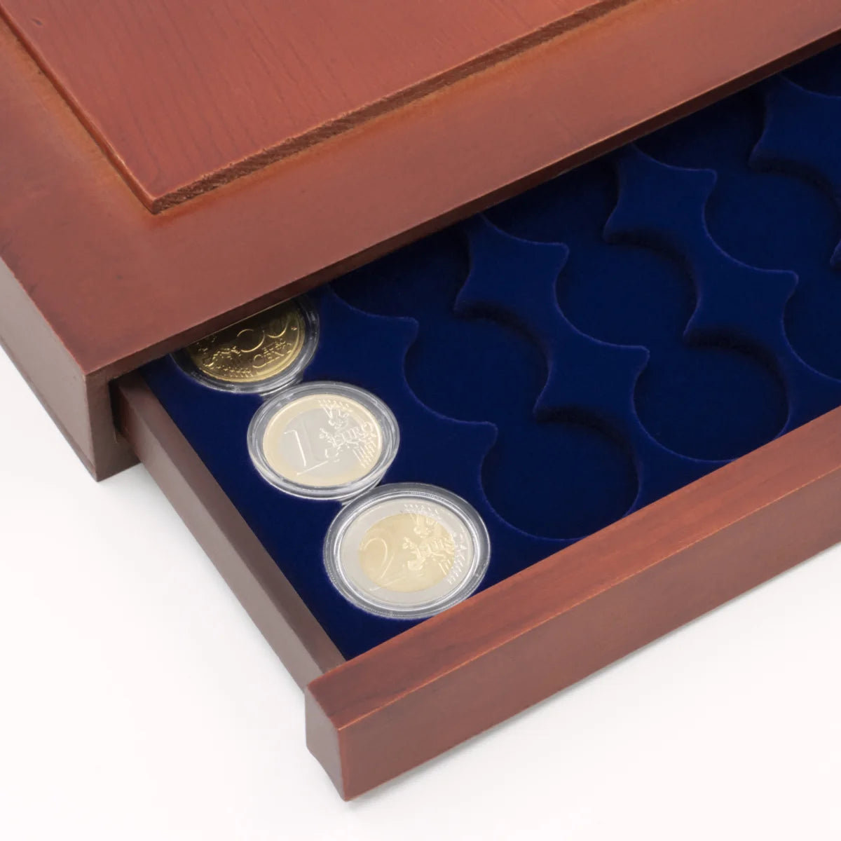 Detail shot of open wooden stackable drawer unit with a blue velvet tray for euro coin sets in capsules on a white background