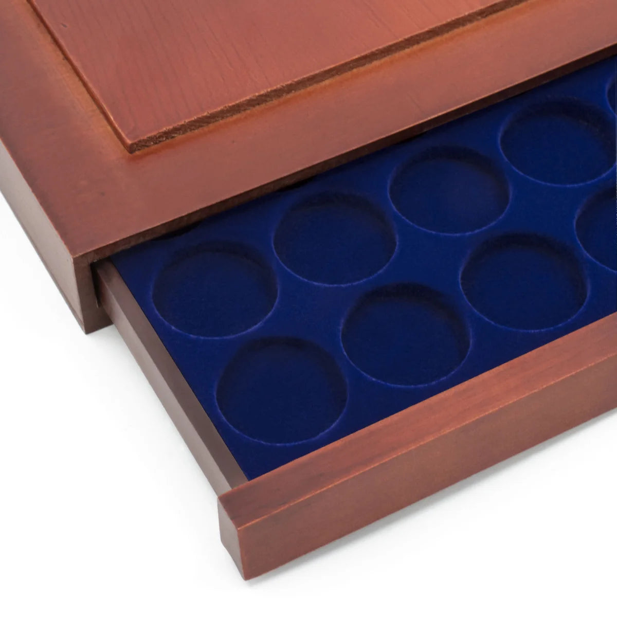Detail shot of open wooden stackable drawer unit with a blue velvet tray with circular compartments holding coins on a white background
