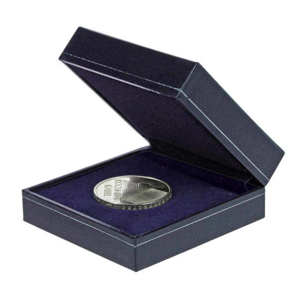 Silver coin in a navy blue box laying on the blue velvet impressionable foam with a blue lining on a white background