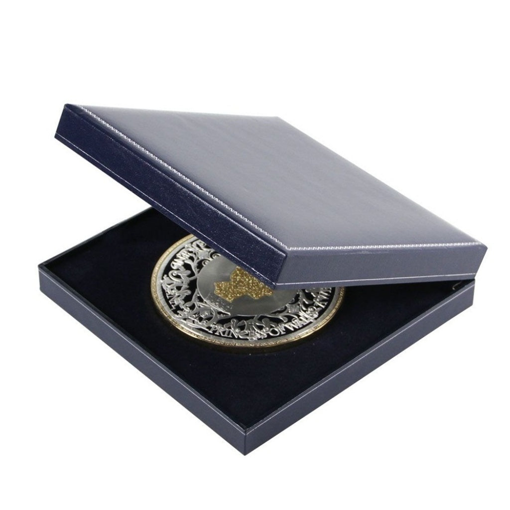 Large silver medallion coin in a navy blue box laying on the blue velvet impressionable foam with a blue lining and the lid open ajar on a white background