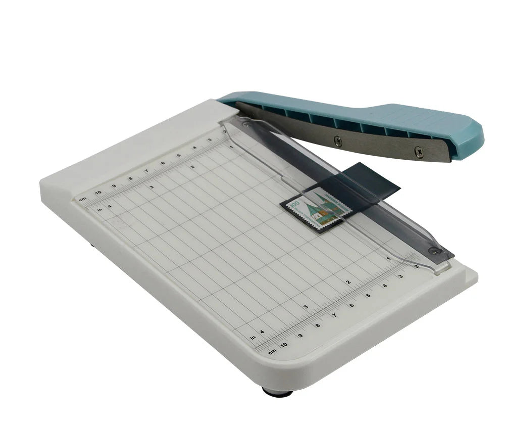 Paper cutter being used on a stamp mount with a inches and centimeter markings on white background