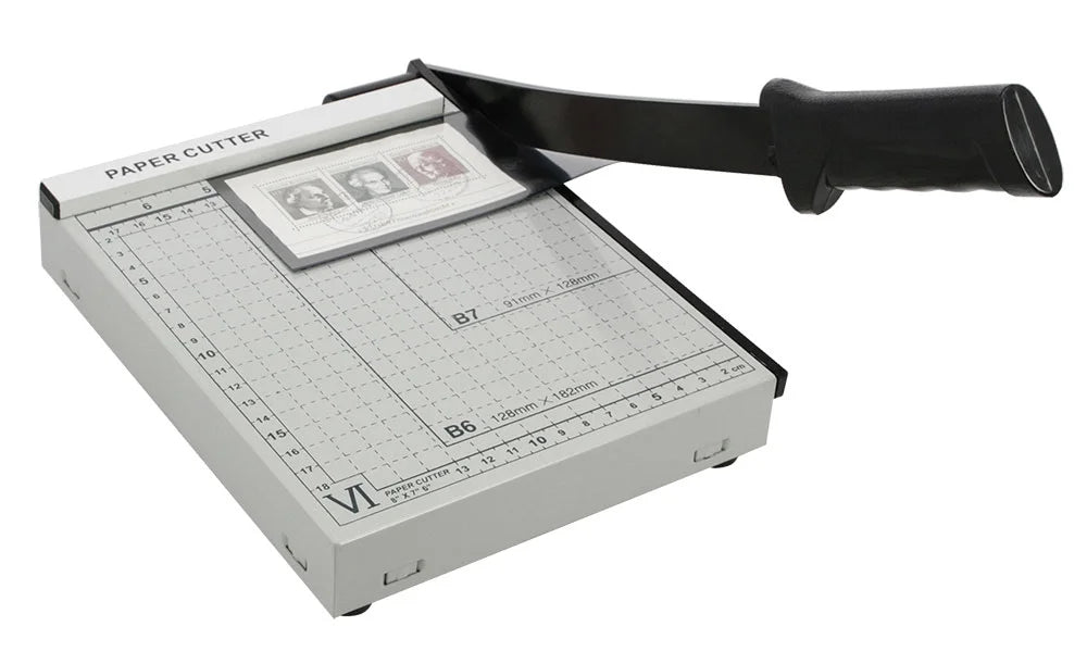 Grey measuring table and black handle paper cutter shown with a stamp mount on a white background