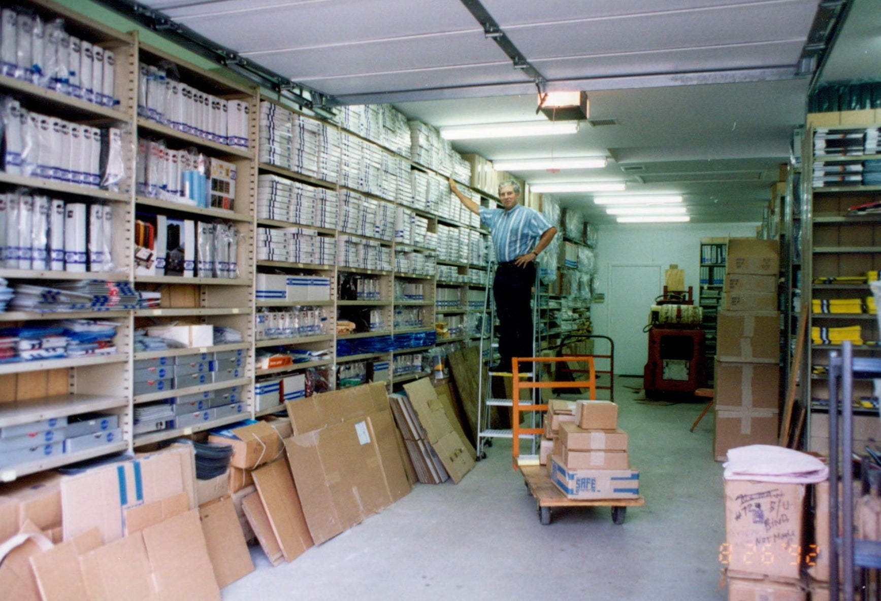 Axel (SAFE founder) in a warehouse with shelves stocked with SAFE products and boxes on the floor.