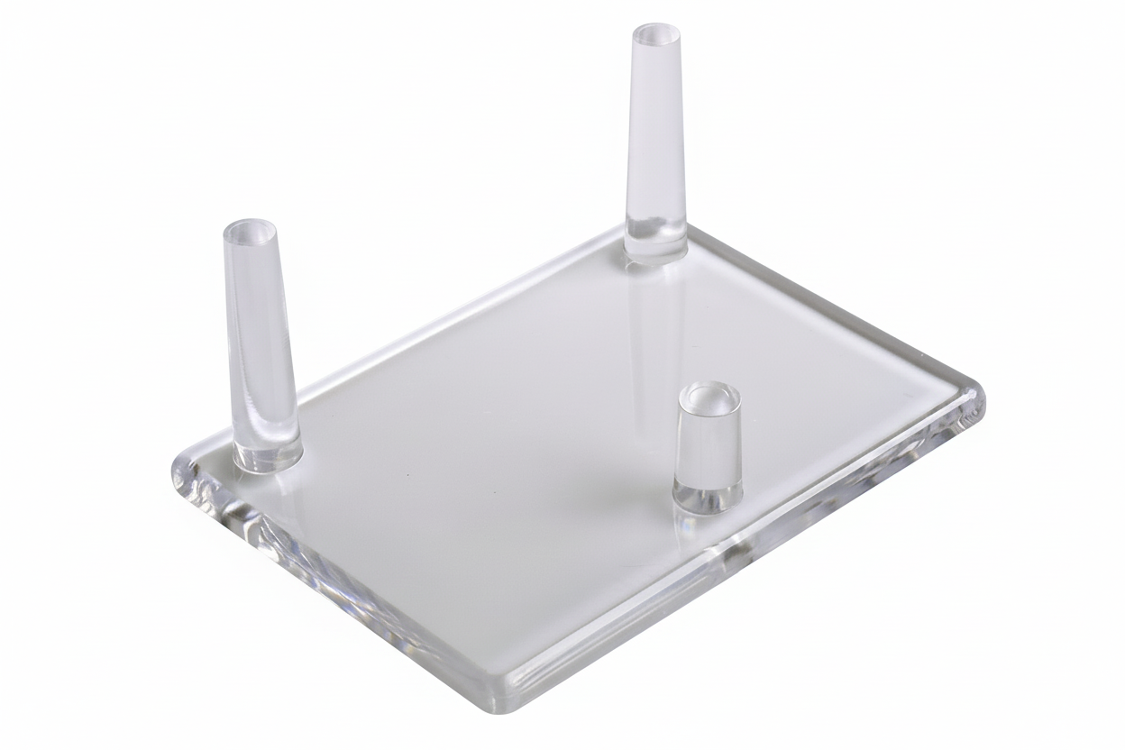 Transparent acrylic display stand with three cylindrical pegs on a white background