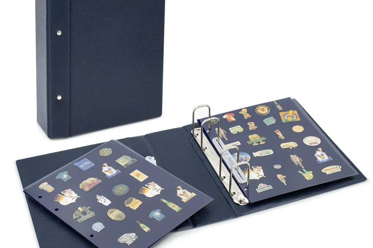 Closed blue collectible album with an open album showing various small collectible pins on velvet pages inside the clear protectors on a white background