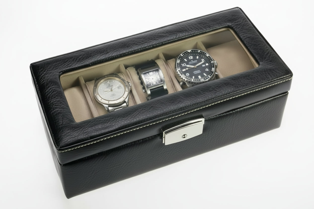 Black watch display case with transparent lid and locking closure revealing 5 beige velvet compartments holding watches and jewelry, on a white background.