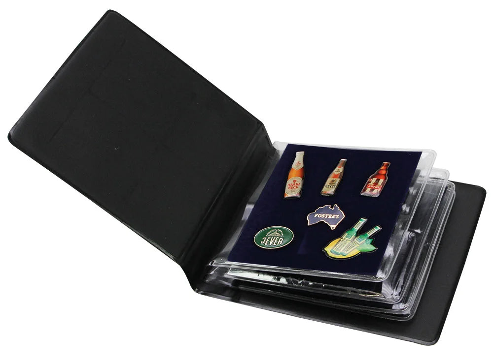 Pocket-sized portable black pin album laid open, revealing collectible pins on a velvet page, on a white background