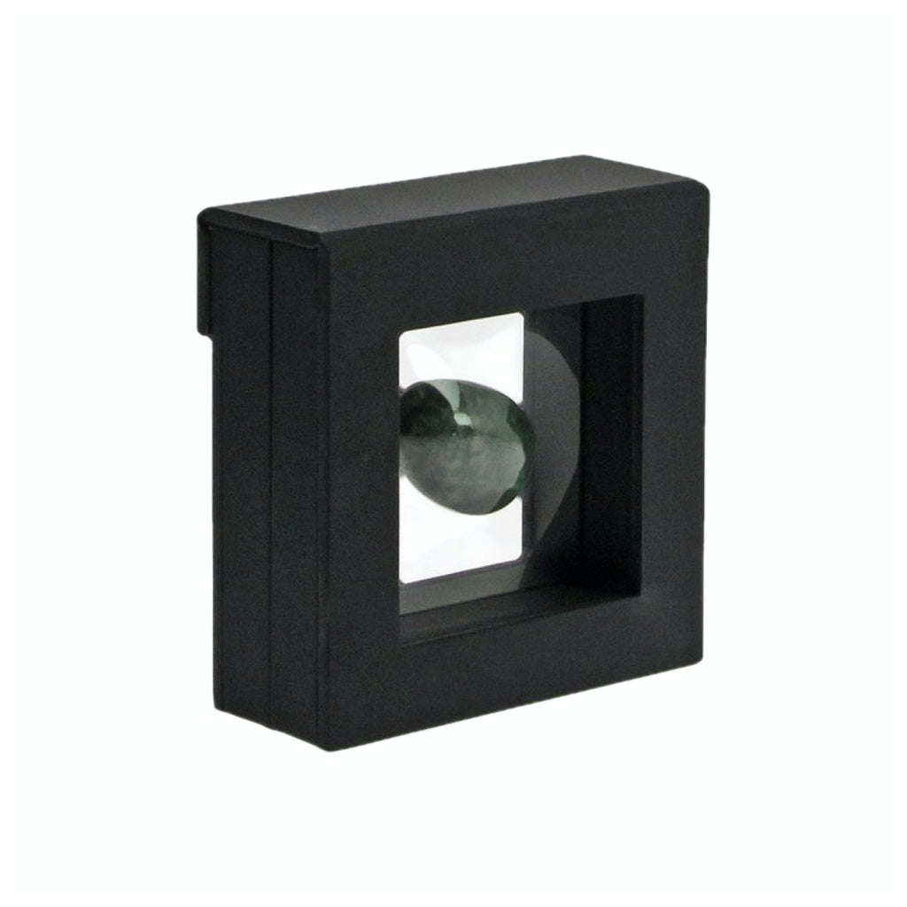 Black square frame with transparent window made of film that is molded to a green mineral on a white background