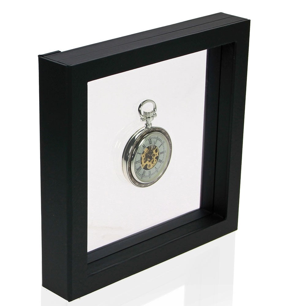 Black square frame/shadowbox with transparent window made of film that is molded to a pocket watch on a white background