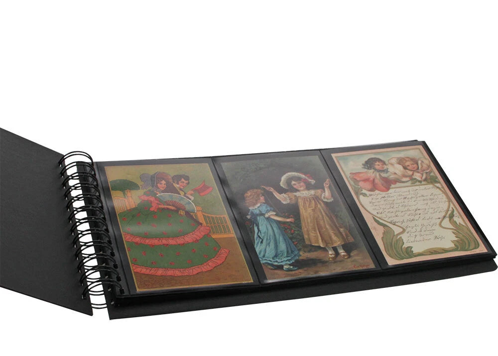 A black spiral-bound album or postcard  book shown open on a white background, displaying three vintage-style printed postcards with illustrated figures and script.