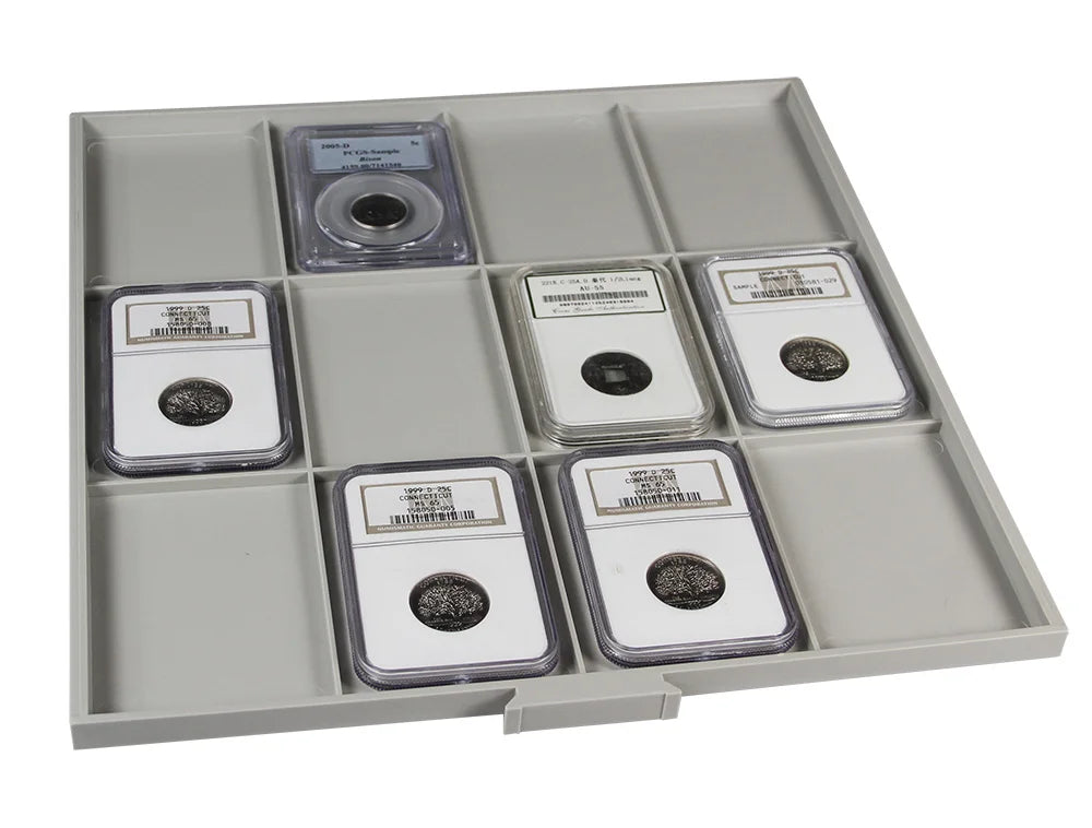 Gray grid coin tray drawer with a collection of graded coin slabs on a white background