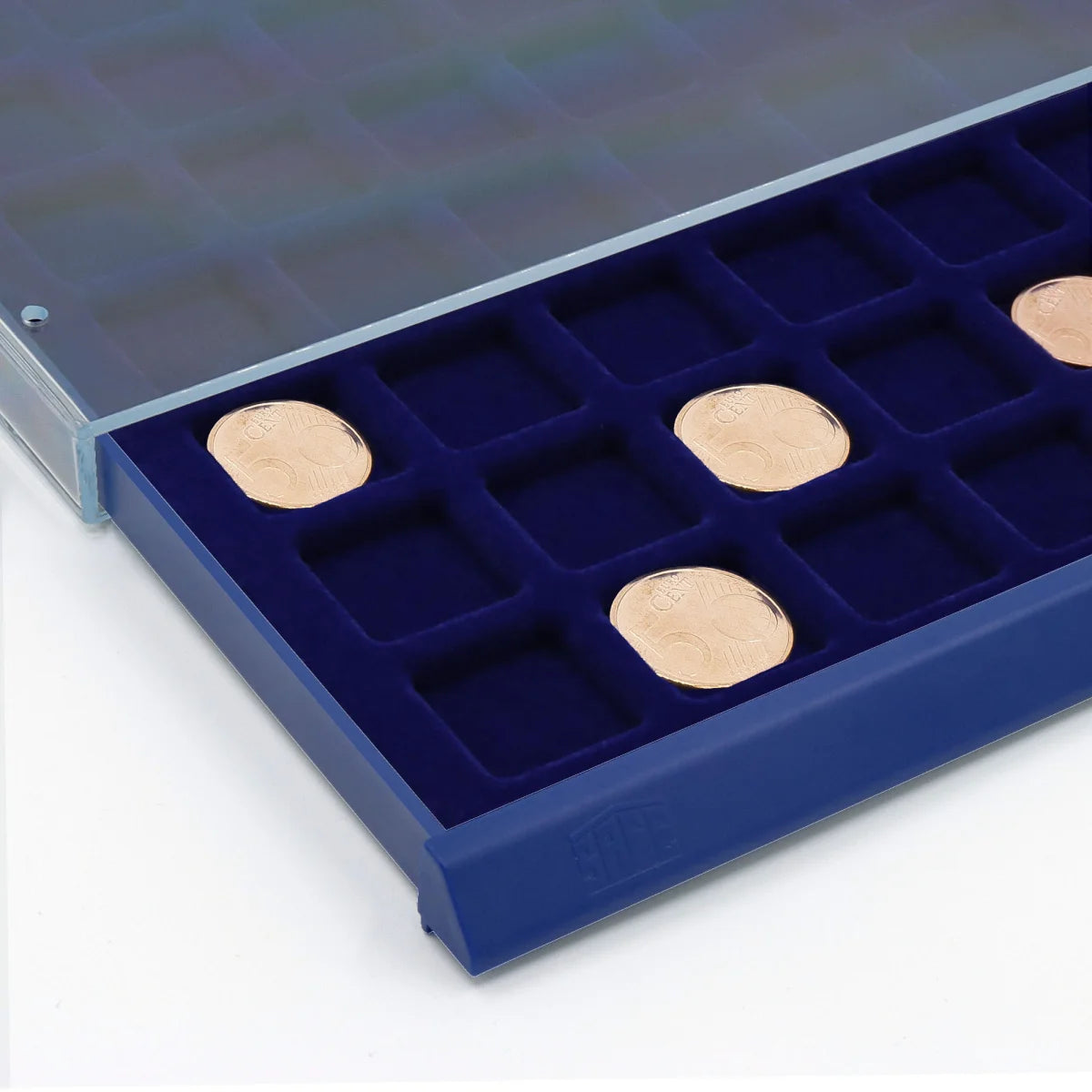 Detail image of open acrylic stackable drawer unit with a blue velvet tray and square compartments with coins on a white background