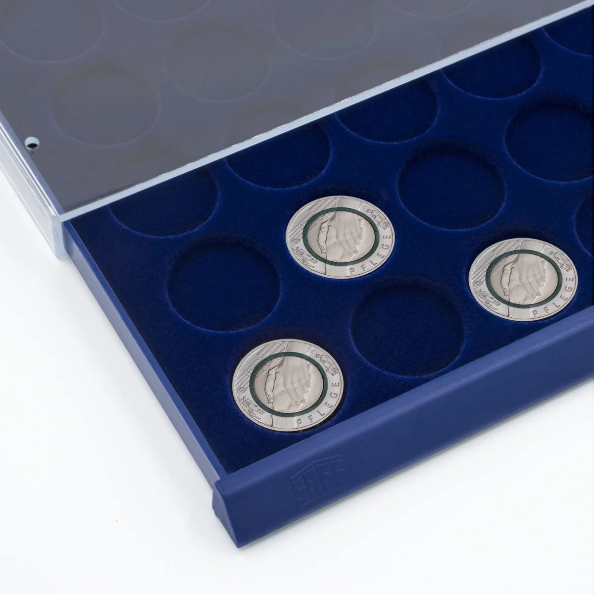 Detail shot of open acrylic stackable drawer unit with a blue velvet tray and circular compartments for coins on a white background