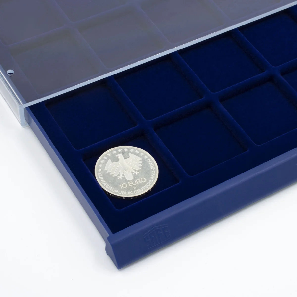 Detail shot of open acrylic stackable drawer unit with a blue velvet tray and square compartments for coins on a white background