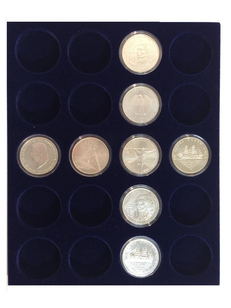 A 12-hole coin display tray with a dark navy blue velvet insert, holding several silver and gold-colored coins in circular protective plastic cases.