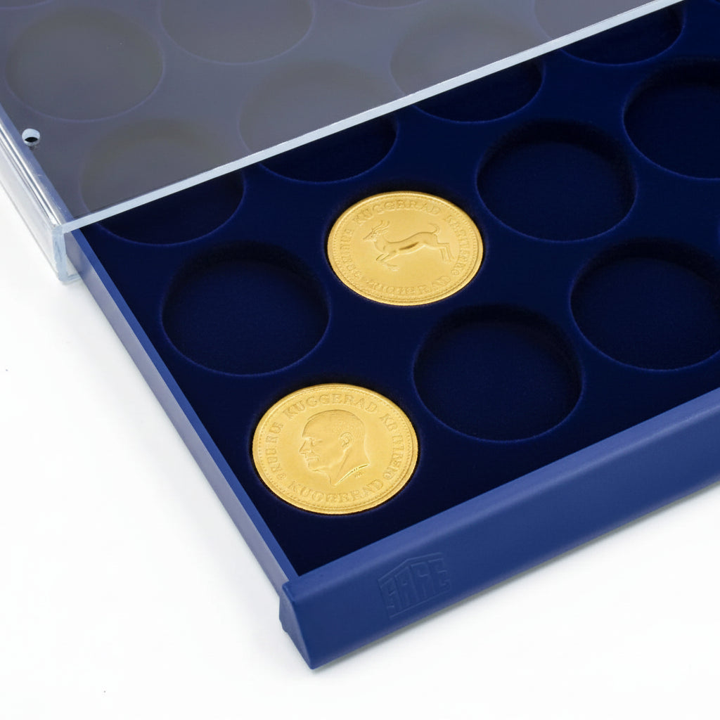 Detail shot of open acrylic stackable drawer unit with a blue velvet tray and circular compartments holding gold coins on a white background