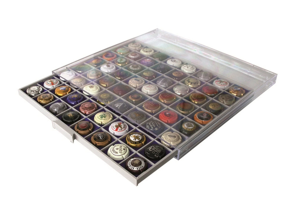 A drawer organizer tray filled with assorted bottle caps, shown on a plain white background.