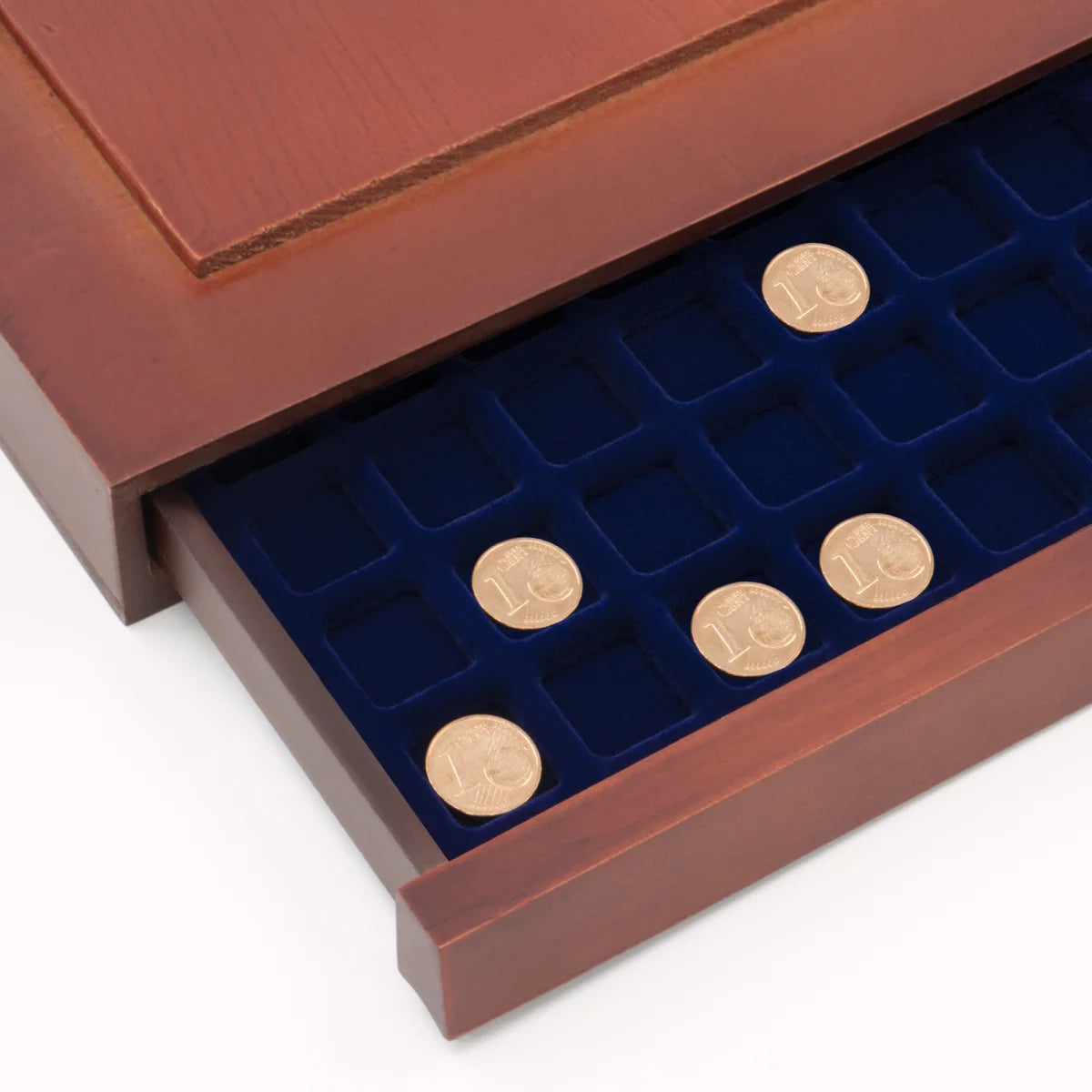 Detail shot of open wooden stackable drawer unit with a blue velvet tray with square compartments holding coins on a white background