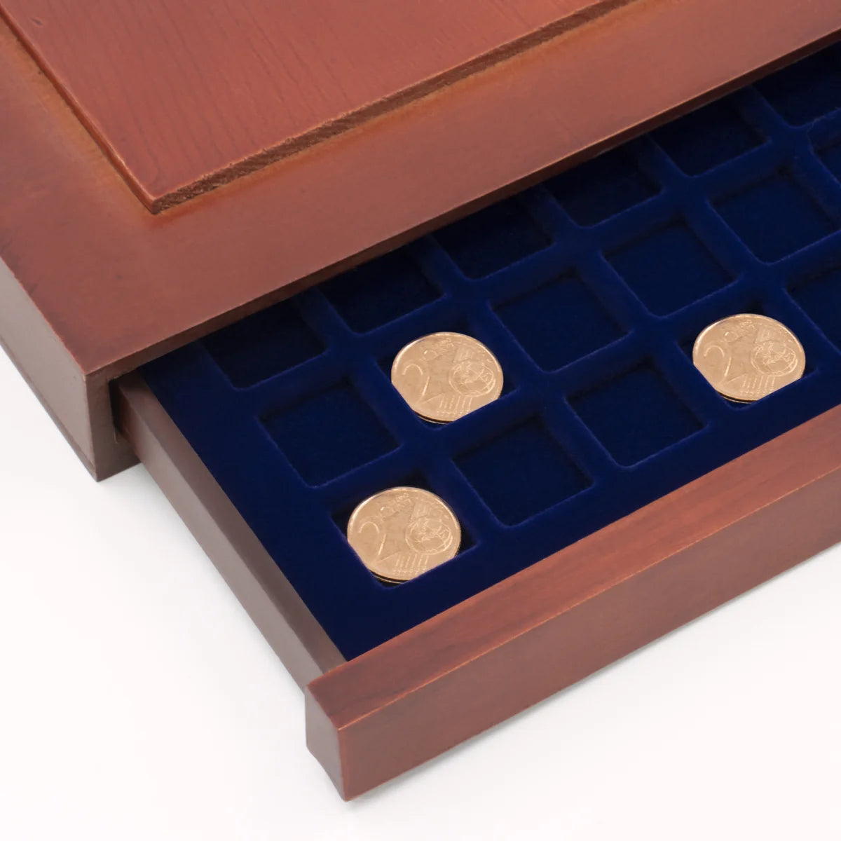Detail shot of open wooden stackable drawer unit with a blue velvet tray with square compartments holding coins on a white background