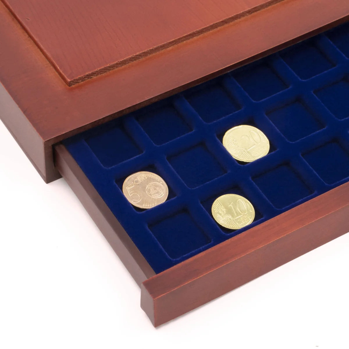 Detail shot of open wooden stackable drawer unit with a blue velvet tray with square compartments holding coins on a white background