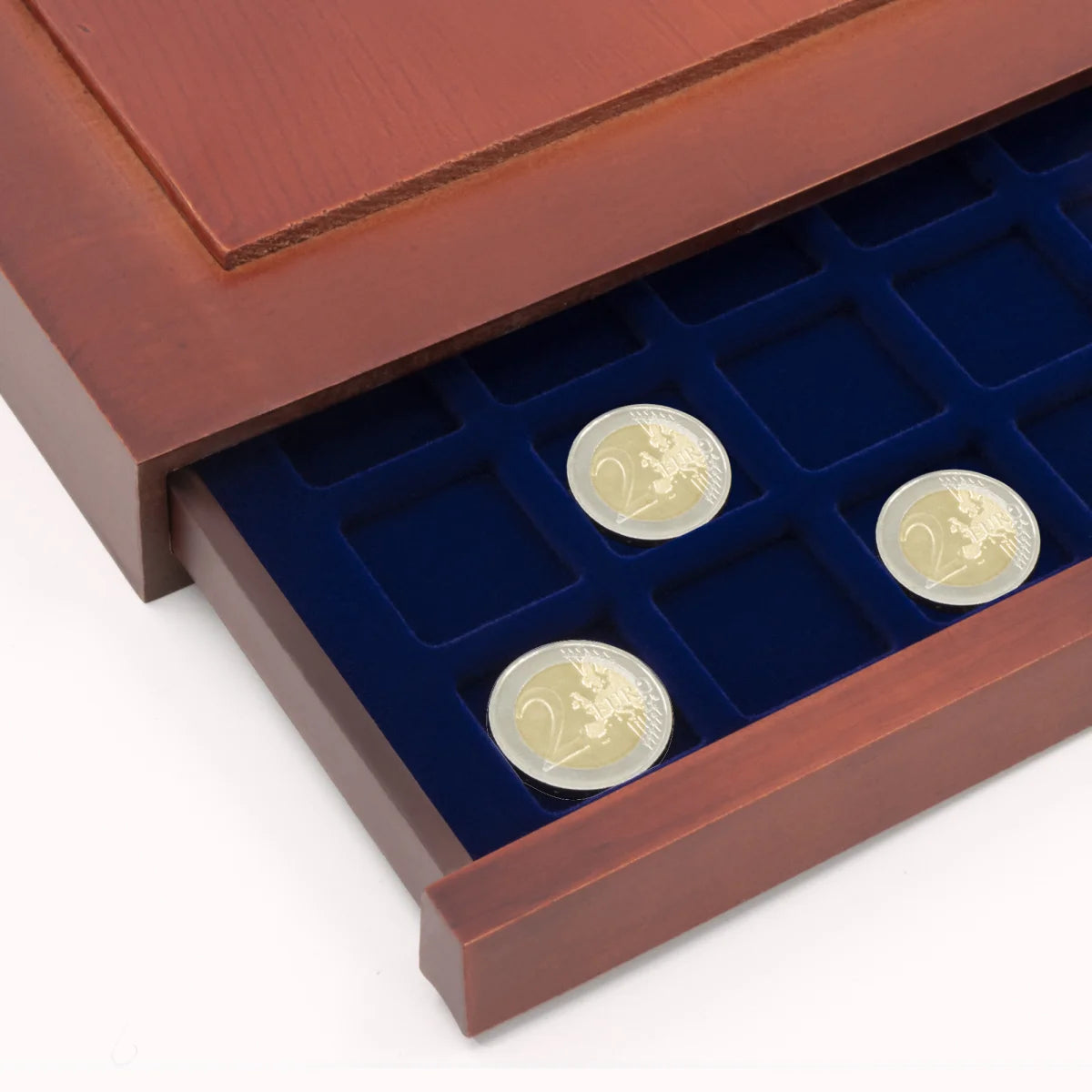 Detail shot of open wooden stackable drawer unit with a blue velvet tray with square compartments holding coins on a white background