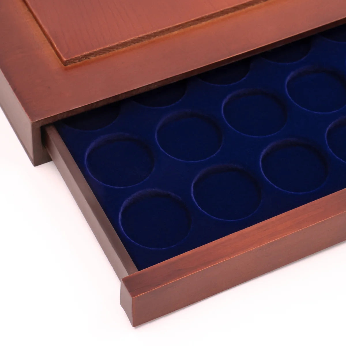 Detail shot of open wooden stackable drawer unit from with a blue velvet tray with circular compartments for coins on a white background