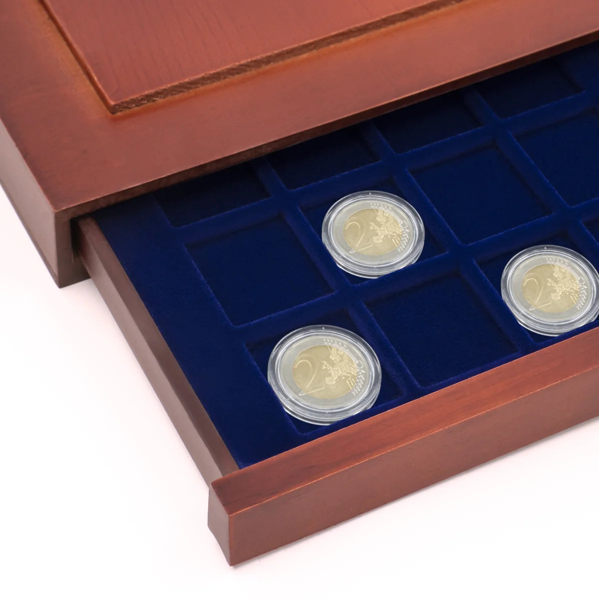 Detail shot of open wooden stackable drawer unit with a blue velvet tray with square compartments holding coins on a white background