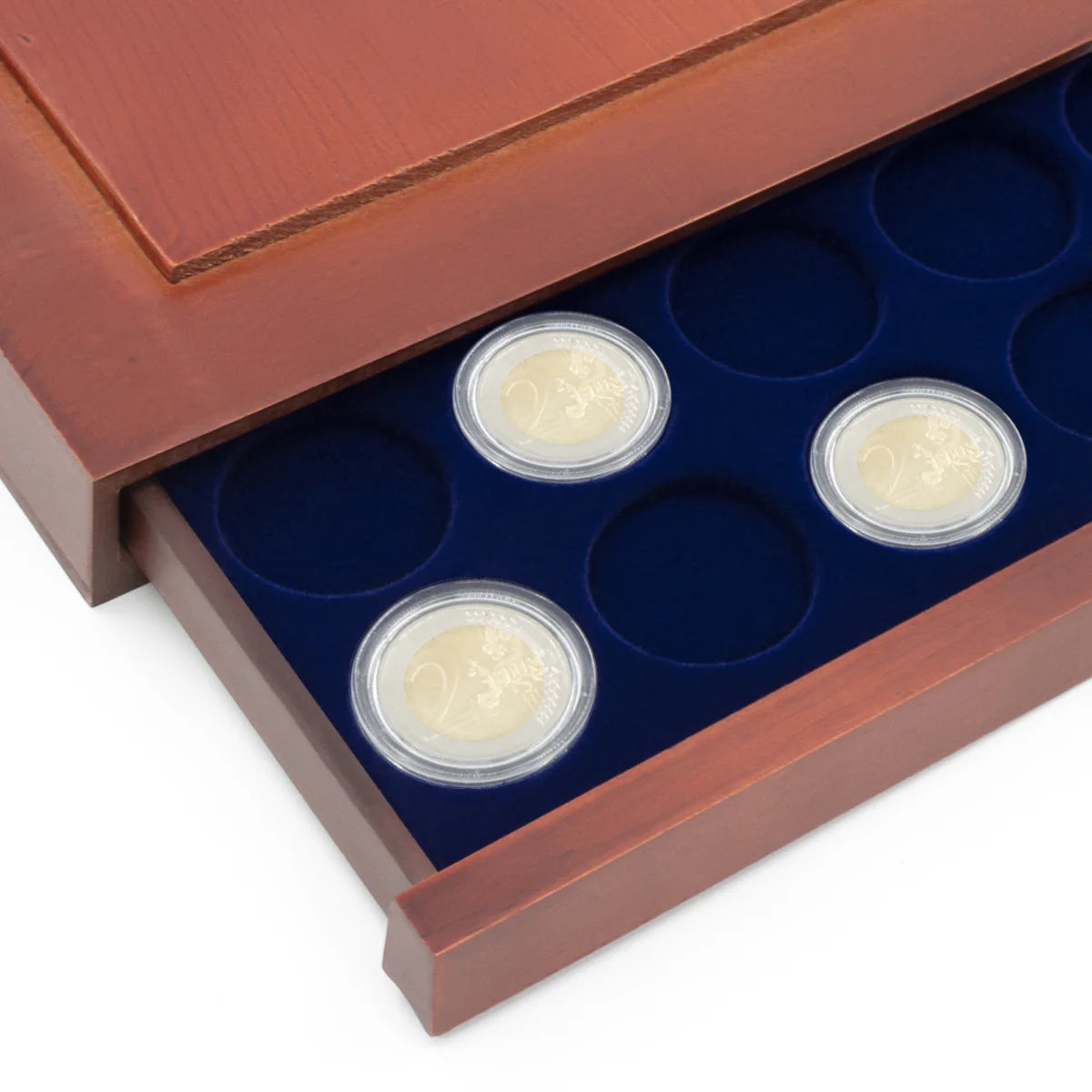 Detail shot of open wooden stackable drawer unit with a blue velvet tray with circular compartments holding coins on a white background