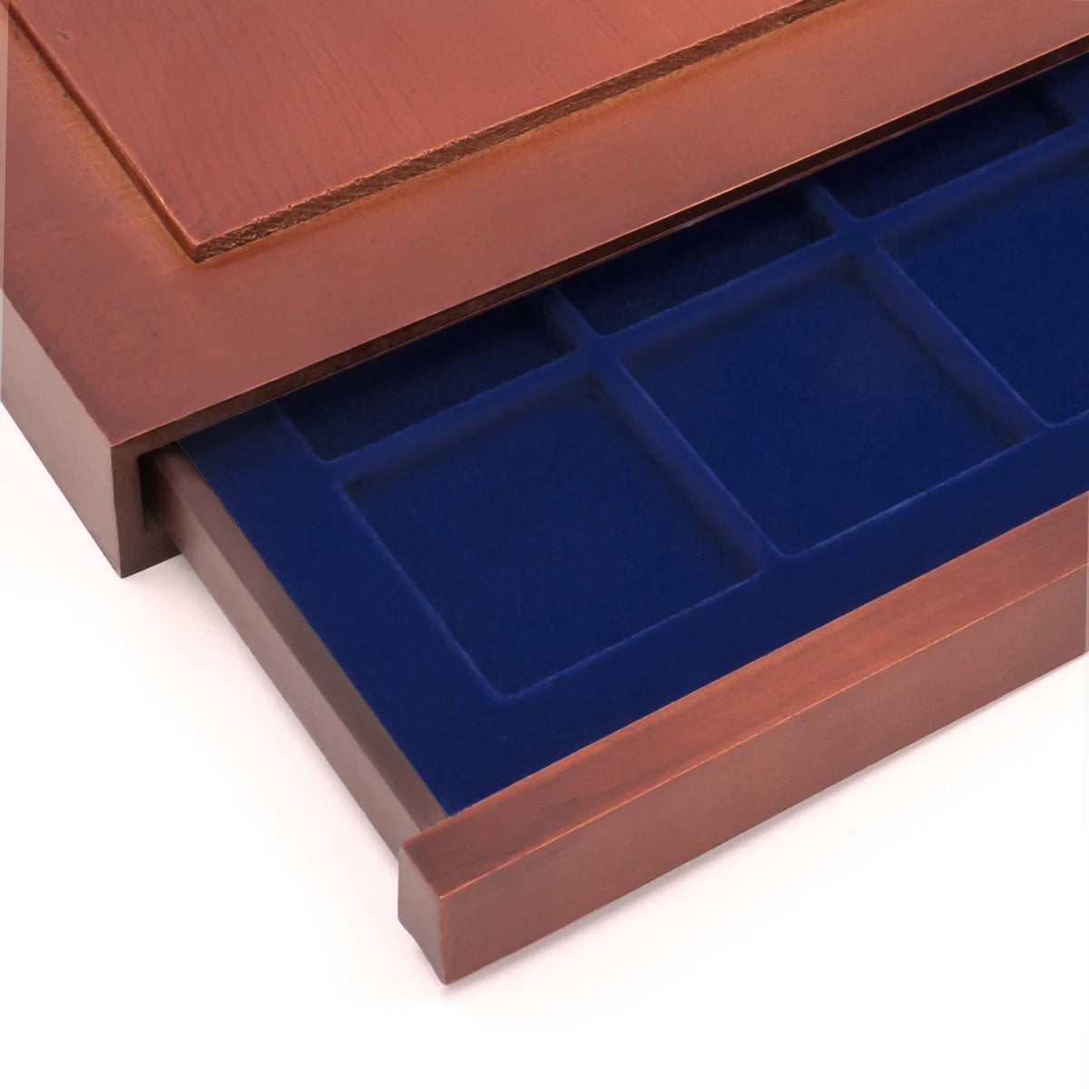 Detail shot of open wooden stackable drawer unit with a blue velvet tray with square compartments for coins on a white background