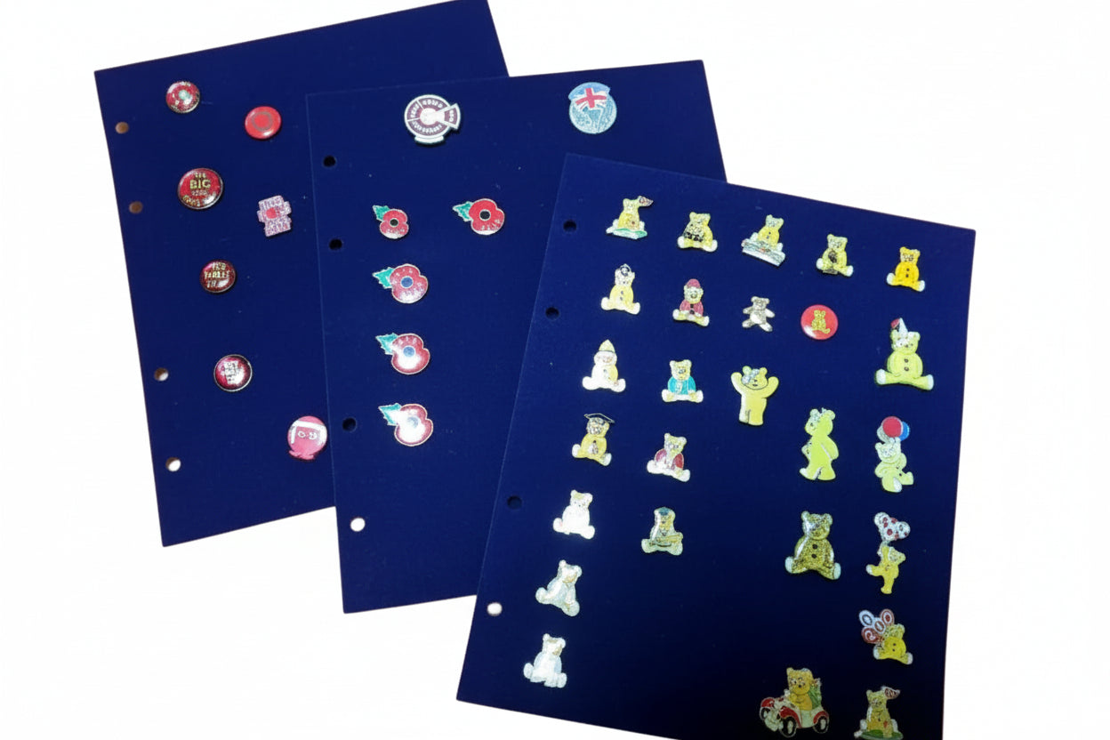Collection of various small pins on a spread of blue velvet album pages on a white background