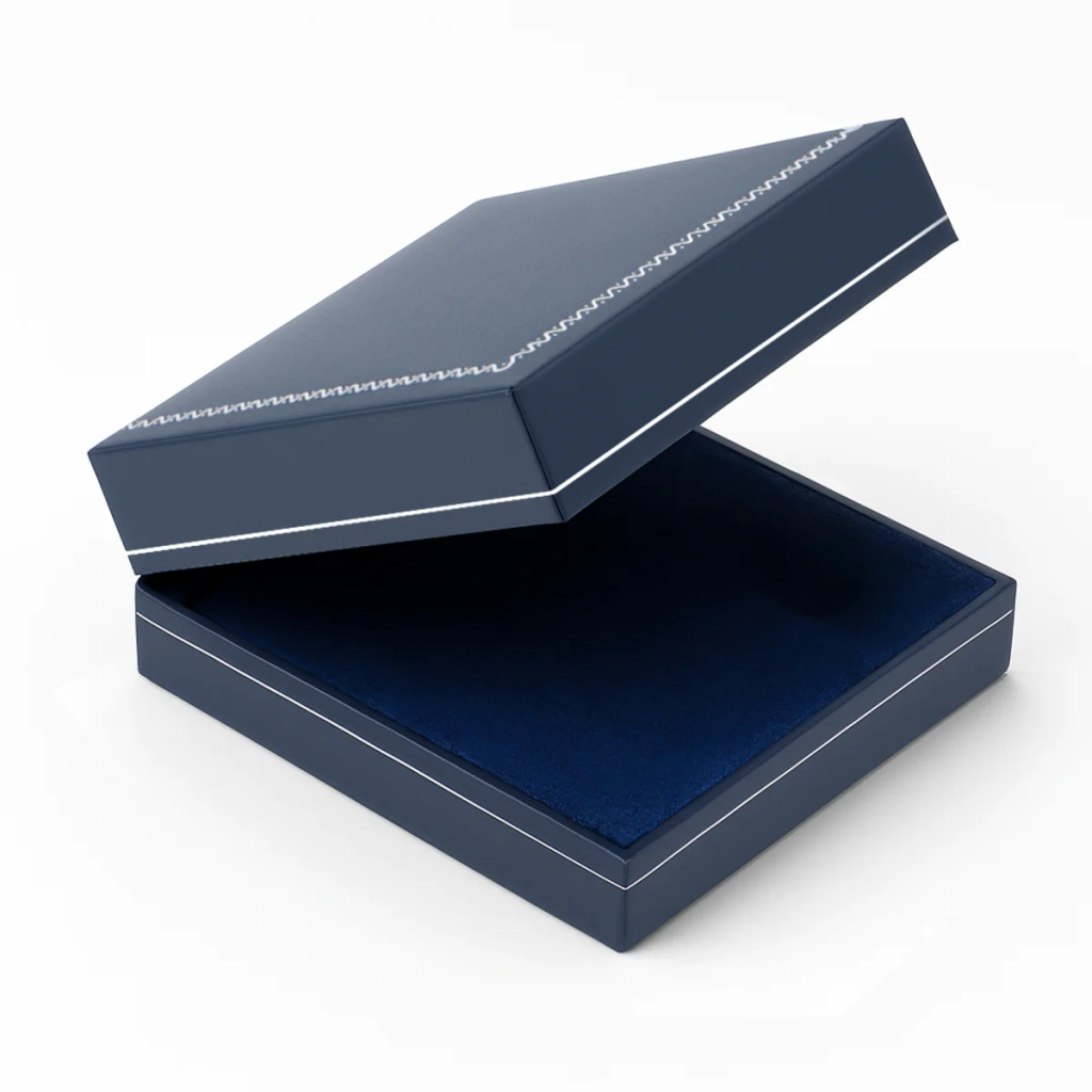 An empty navy blue box with a blue velvet impressionable foam insert and blue lining with the lid open ajar on a white background
