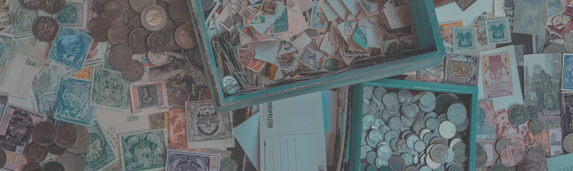 Collection of stamps, coins, postcards and more spread out, filling the entire image